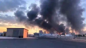 Heavy black smoke engulfing urban sky behind industrial facilities and road network
