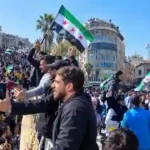 Large crowd waving Syrian opposition flags during public demonstration in Damascus
